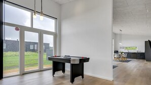 Una habitación amplia con mesa de billar, ventanas grandes y vistas al exterior.