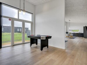 Een ruime kamer met een pooltafel, grote ramen en uitzicht op het landschap.
