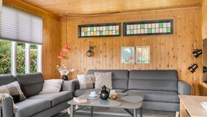 Ein gemütliches Zimmer mit grauem Sofa, einem Couchtisch und einer Holzbodenverkleidung.