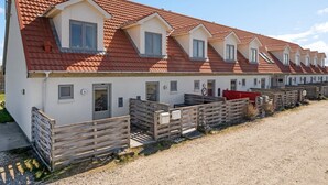 Eine Reihe weißer Gebäude mit roten Ziegeldächern und kleinen Fenstern, jeweils mit einem Holzzaun im Vordergrund.