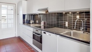 Eine moderne Küche mit weißen Schränken, einer schwarzen Küchenzeile, Edelstahlgeräten und einer doppelten Spüle.