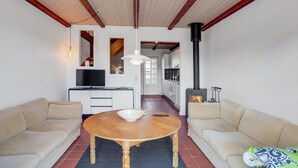 Ein gemütliches Wohnzimmer mit einem Holztisch, zwei Sofas, einem Fernseher und einem Kamin.
