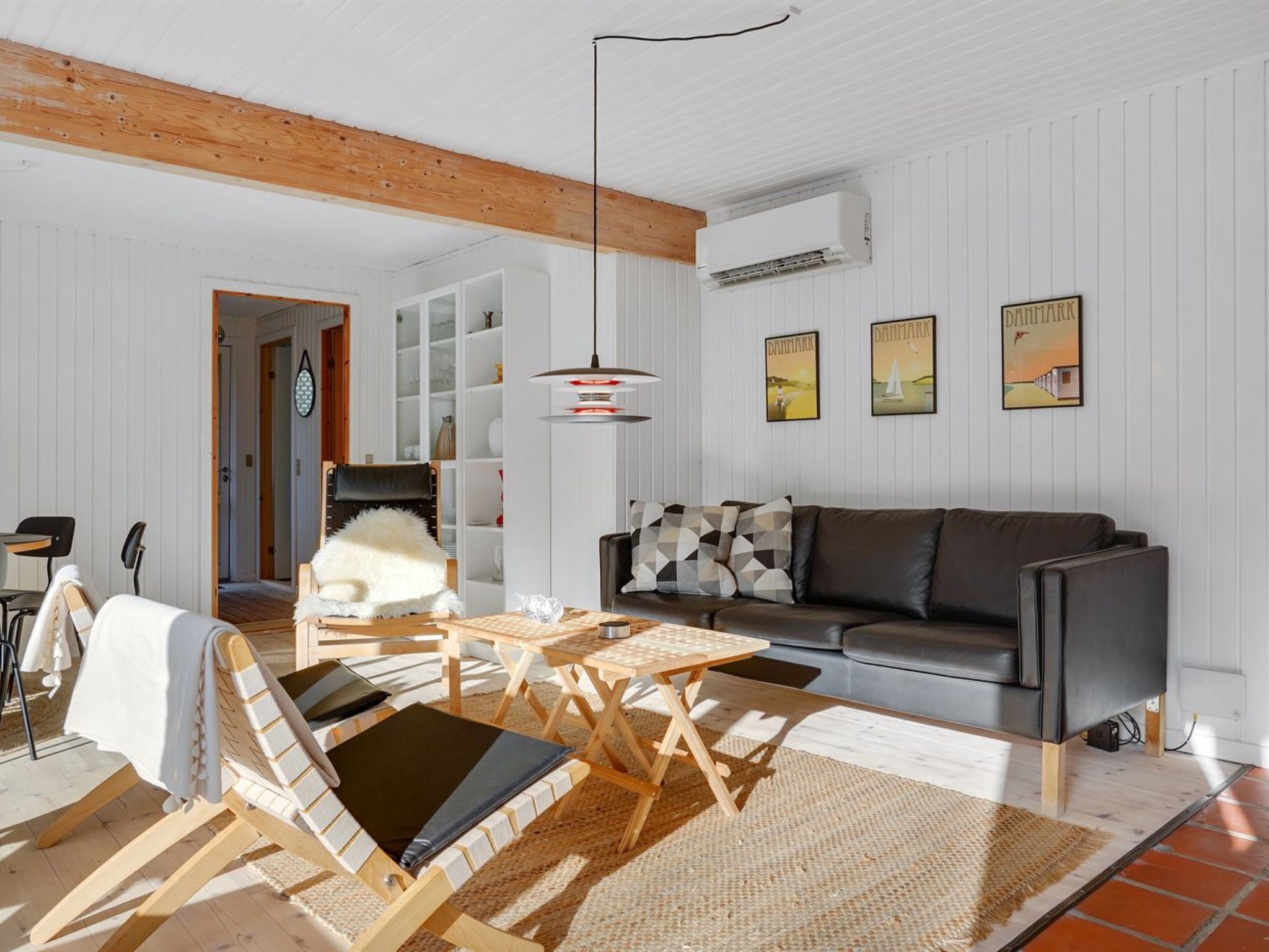 Una sala de estar moderna con techo de madera, un sofá gris, una mesa de centro de madera y un ventanal grande.
