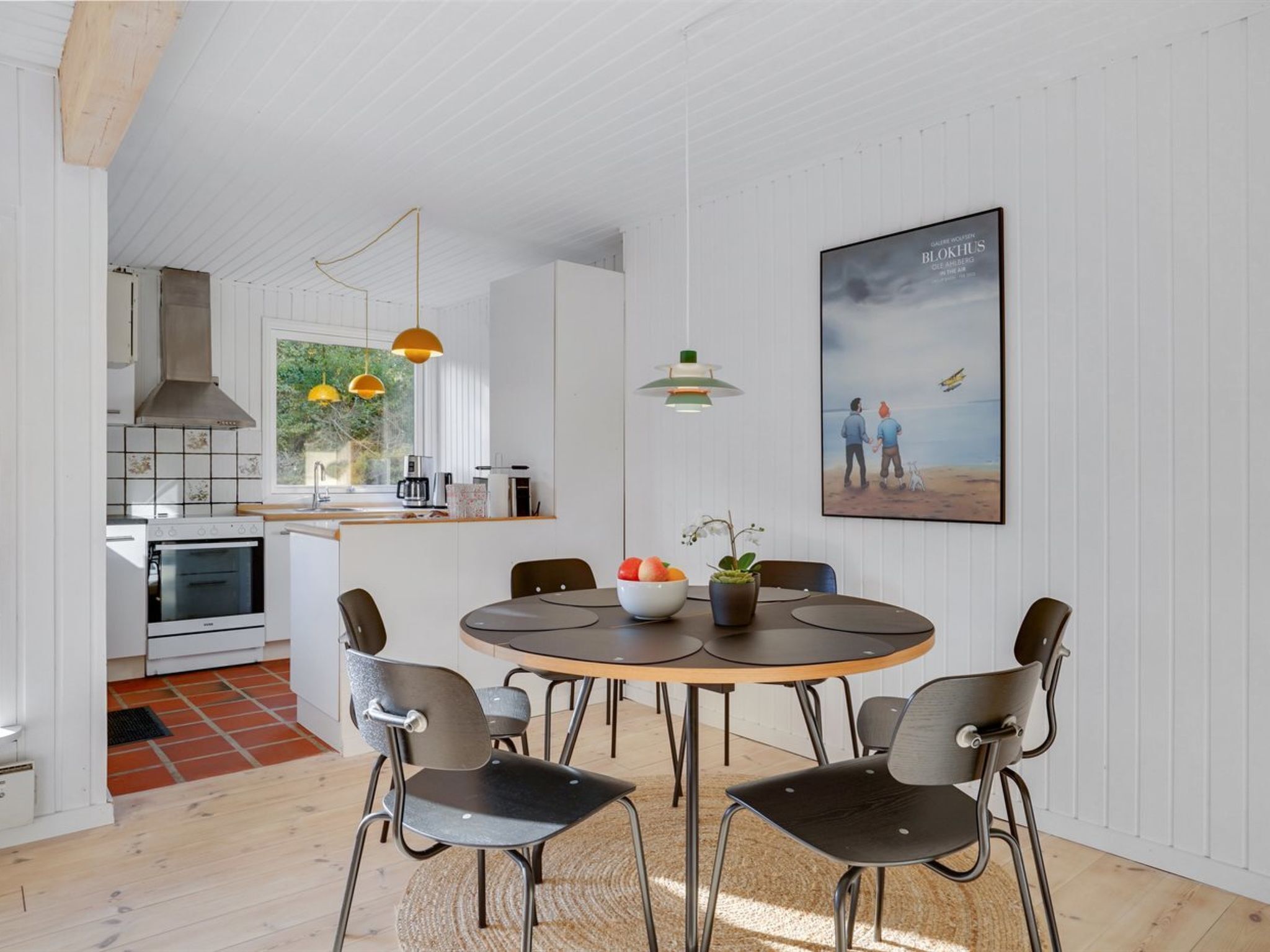 Une cuisine moderne avec des meubles blancs, un îlot central et des luminaires suspendus.