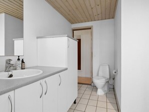 Baño con lavamanos, espejo e inodoro blancos.