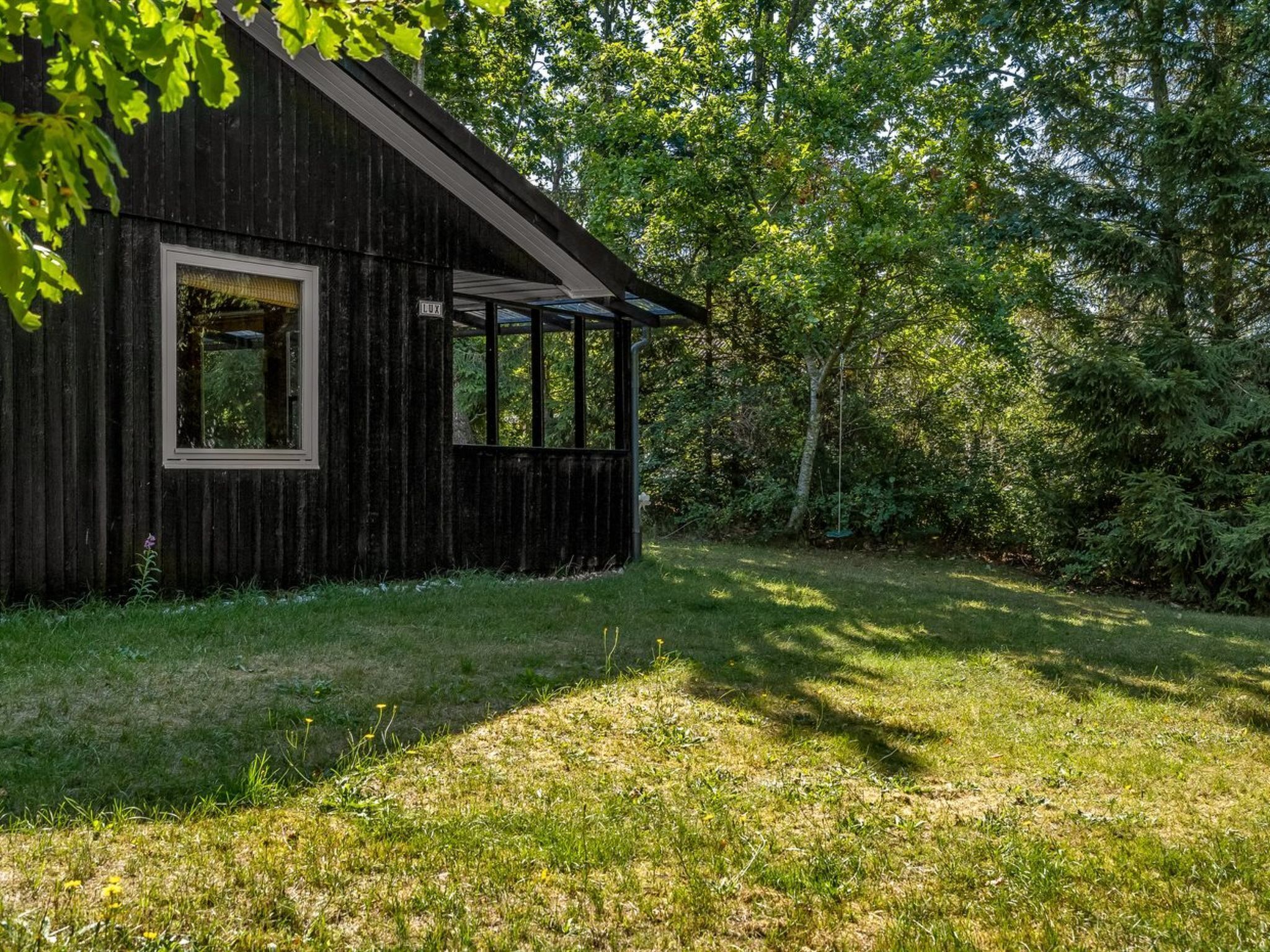 A rustic wooden building with a large window and a covered porch area.