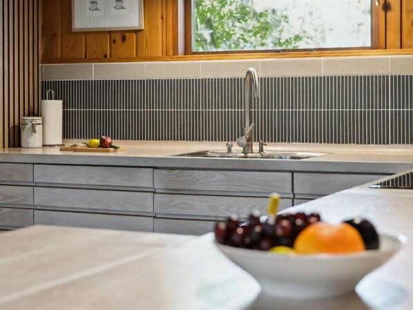 Una cocina de diseño moderno, con un lavamanos grande, una encimera de madera y un bol de fruta.