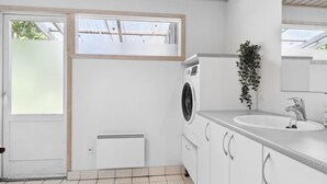 Un baño moderno con lavadora, lavamanos y ventana.