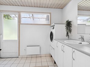 Een moderne badkamer met een wasmachine, een wastafel en een raam.