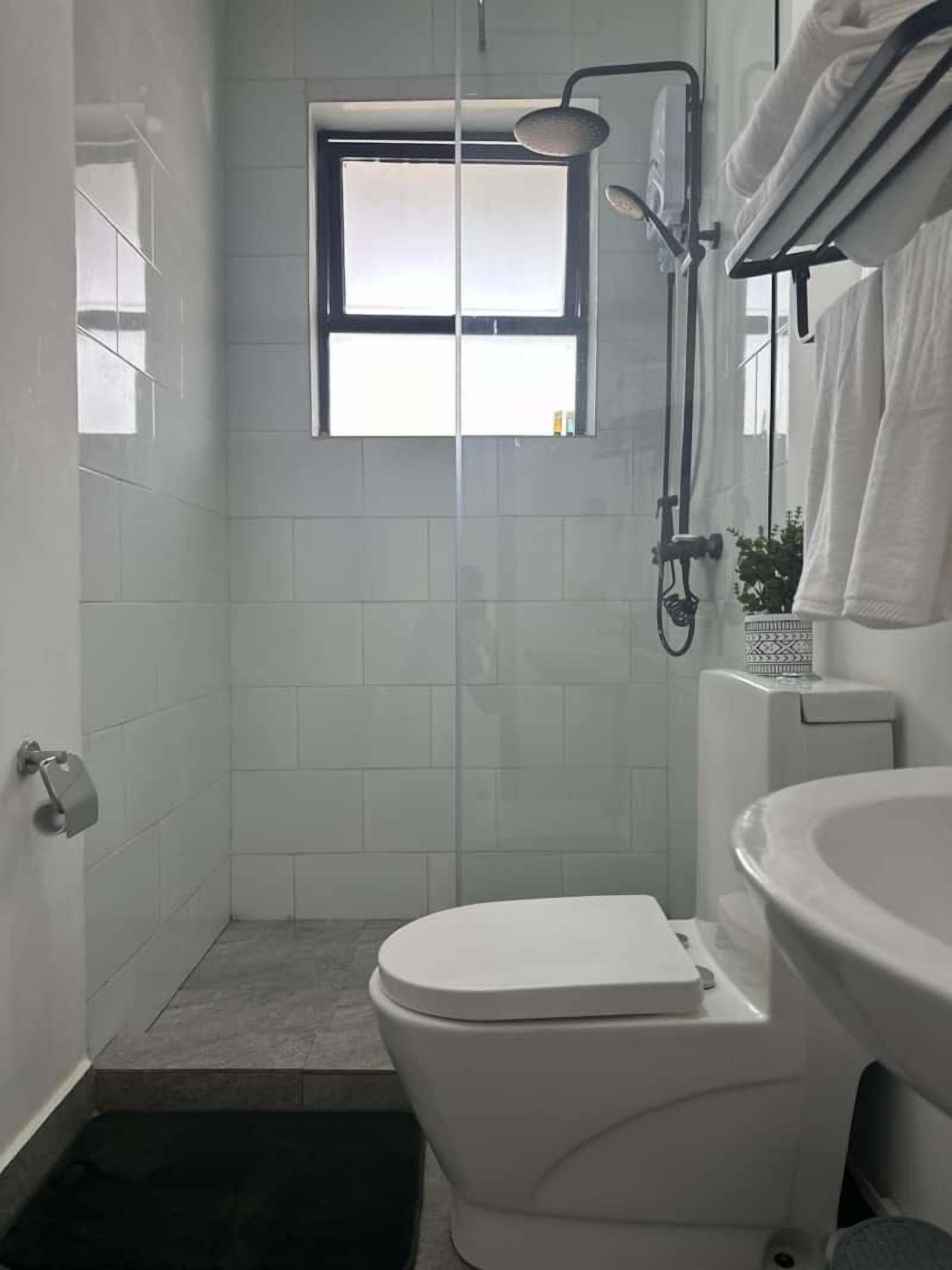 A small, modern bathroom with a toilet, a shower, and a sink.