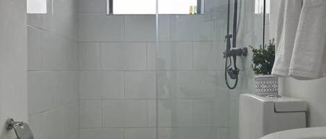 A small, modern bathroom with a toilet, a shower, and a sink.