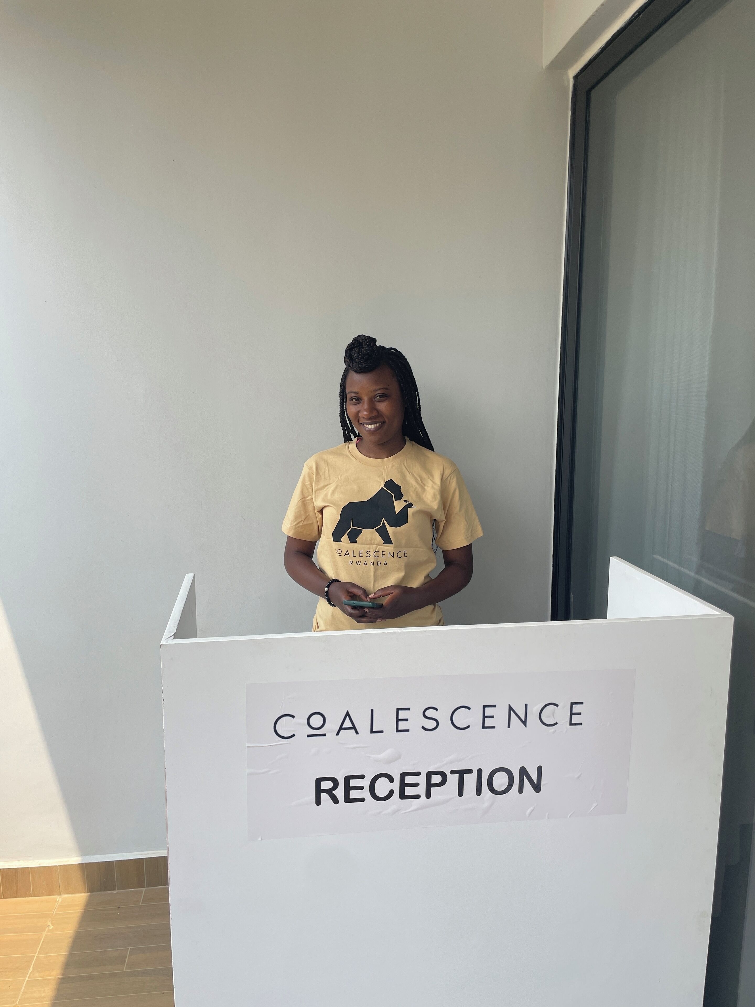 A person standing at a reception desk with a sign that reads "COALESENCE RECEPTION".
