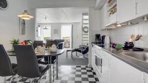 A modern kitchen with white cabinets, a black and white checkered floor, and a dining area with black chairs and a table. - "Maura" - 2.3km from the sea by Interhome (Rømø)