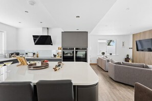 A modern kitchen with a central island, built-in appliances, and a flat-screen TV.