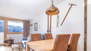Una mesa de comedor de madera con seis sillas, una lámpara colgante y un ventanal con vistas a montañas.