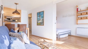 Una sala moderna con sofá, mesa de comedor, lámpara colgante, cama y estantería.