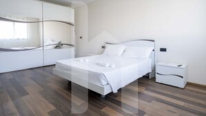 A modern bedroom with a bed, nightstand, and built-in wardrobe.
