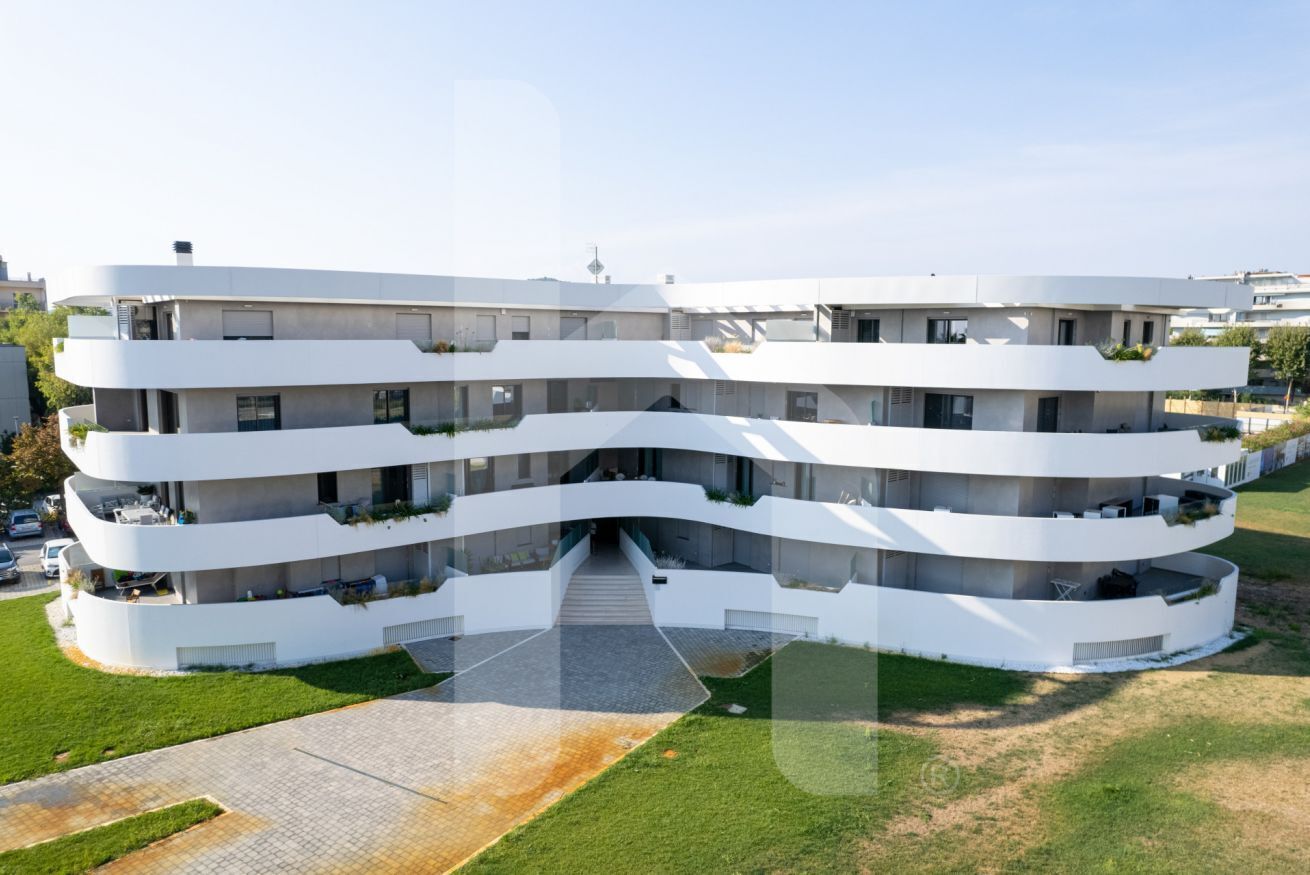 A multi-story residential building with a curved facade, balconies, and a central entrance.