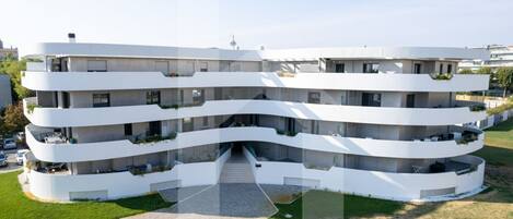 A multi-story residential building with a curved facade, balconies, and a central entrance.