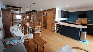 Cozinha moderna com armários de madeira, área de jantar com mesa e cadeiras de madeira e uma pequena ilha com pia.