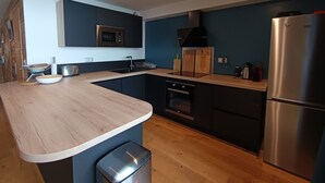 Uma cozinha moderna com bancada de madeira, micro-ondas embutido, geladeira de aço inoxidável e lava-louças.
