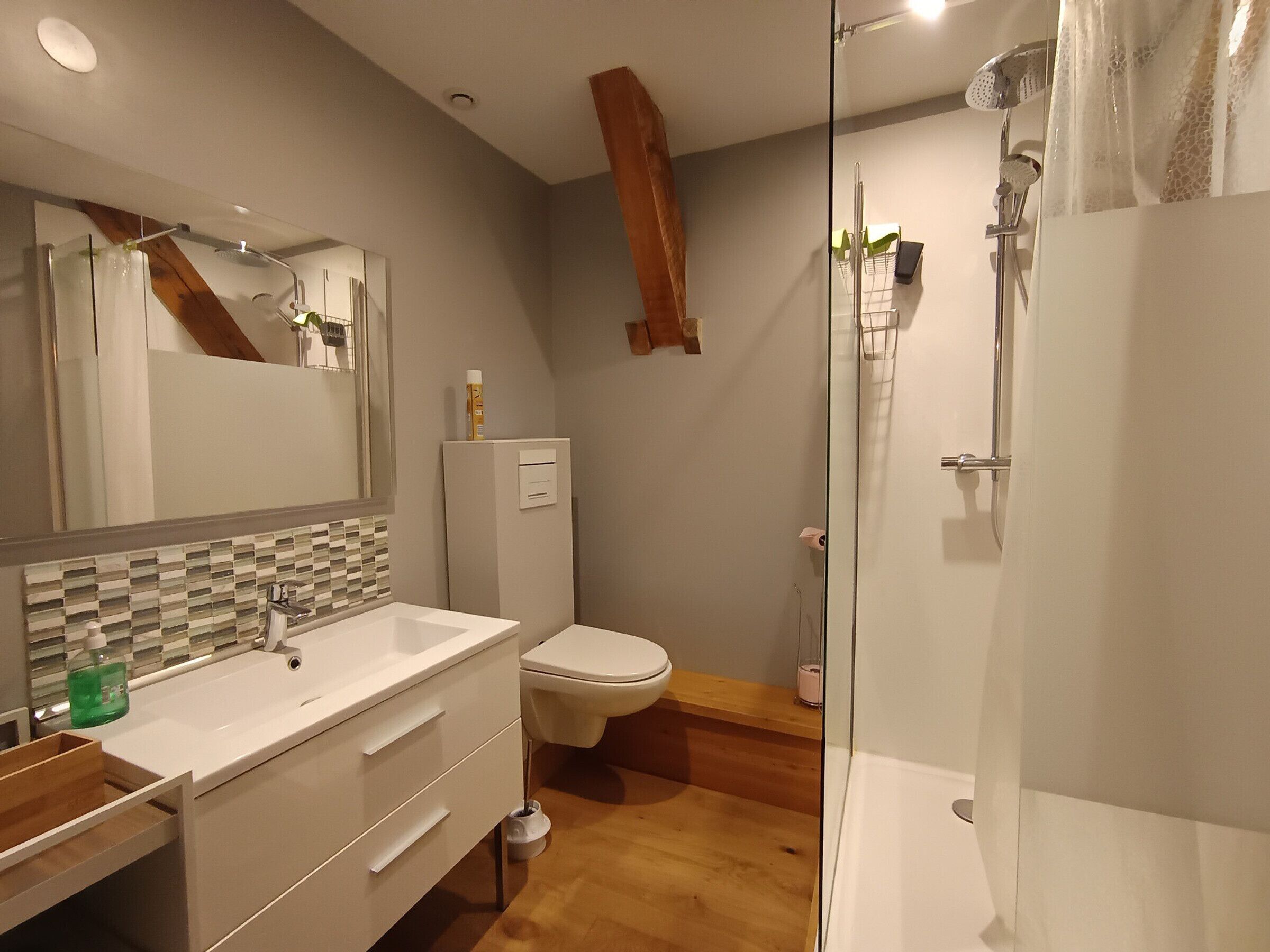 Un baño moderno con cabina de ducha de vidrio, un lavamanos blanco y un inodoro.
