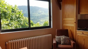 Une pièce chaleureuse avec une grande fenêtre, un radiateur, un fauteuil en cuir marron, une table blanche et des meubles en bois.
