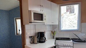 Une cuisine compacte avec des meubles blancs, un four à micro-ondes, une machine à café, une bouilloire et un four.
