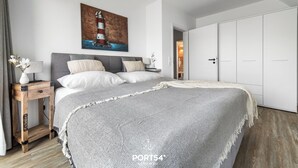 A bedroom with a bed, a nightstand, a painting, and a wardrobe. - Ferienhaus Wellenrauschen - Terrasse, Balkon, Sauna, Kamin, Nordsee- & Strandnah (Büsum)