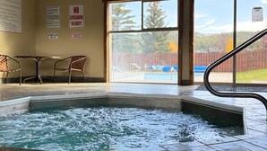 Ein Whirlpoolbereich mit Blick auf einen Pool und eine Holzzahlung.