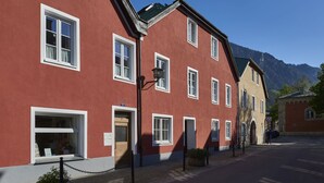 Punainen rakennus, jossa on valkoiset ikkunat ja ovi, katulamppu ja taustalla vuori.