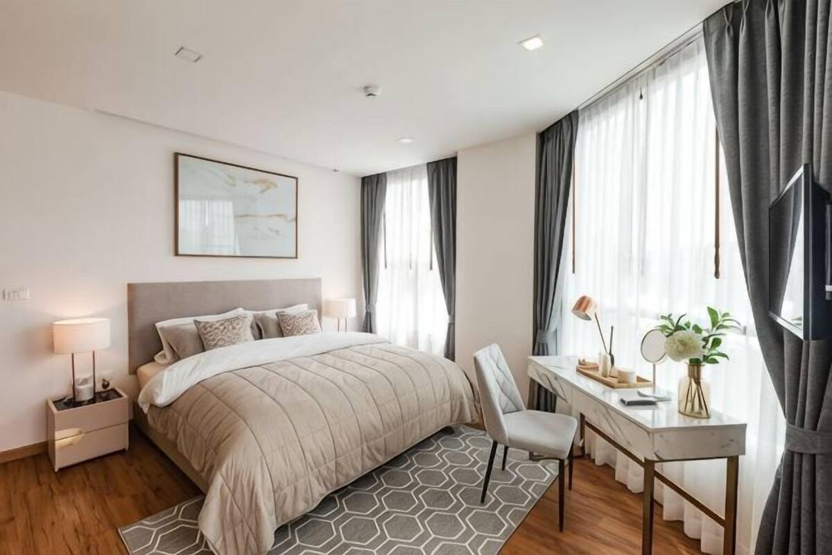 Un dormitorio moderno con cama, mesitas de noche, un escritorio y una silla.