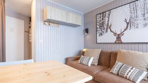 A cozy room with a wooden table, a brown sofa with patterned cushions, a mounted artwork of a deer, and a white door labeled "KEYS".