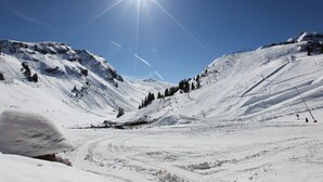 A snow-covered mountain landscape with ski slopes and a clear blue sky.