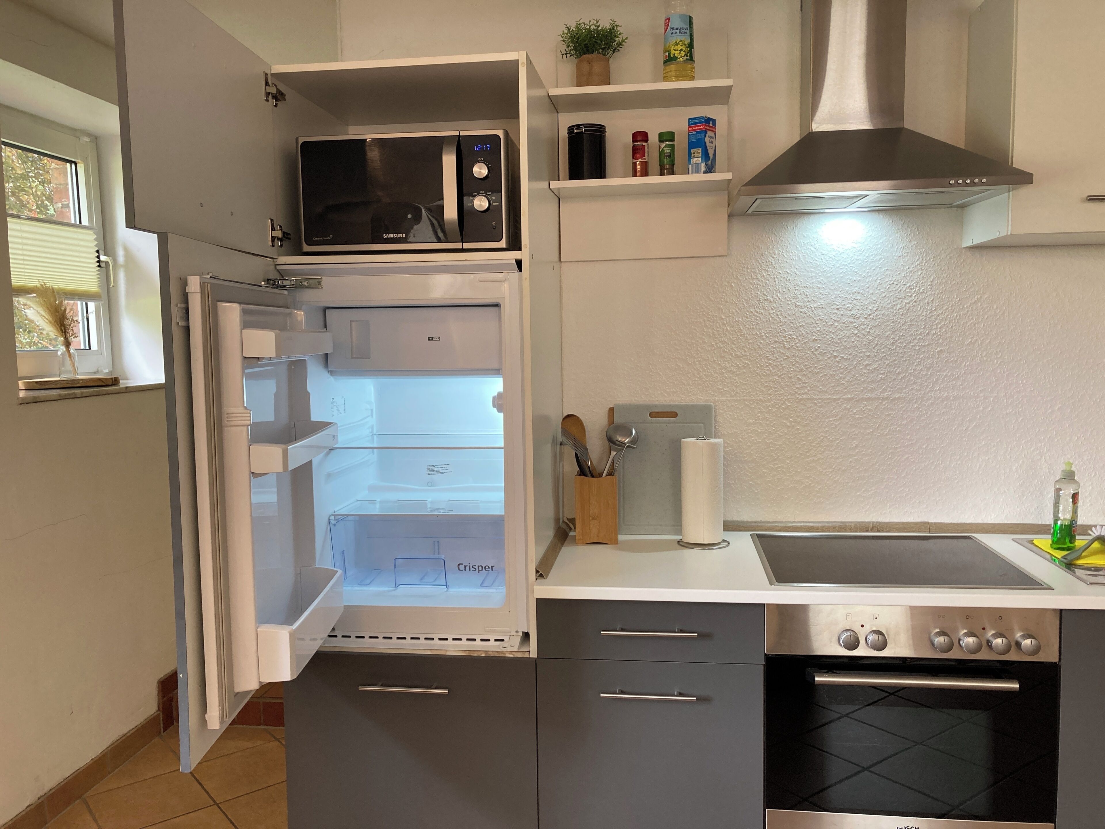 Una cucina accessoriata con forno a microonde, frigorifero, forno e diversi utensili da cucina.