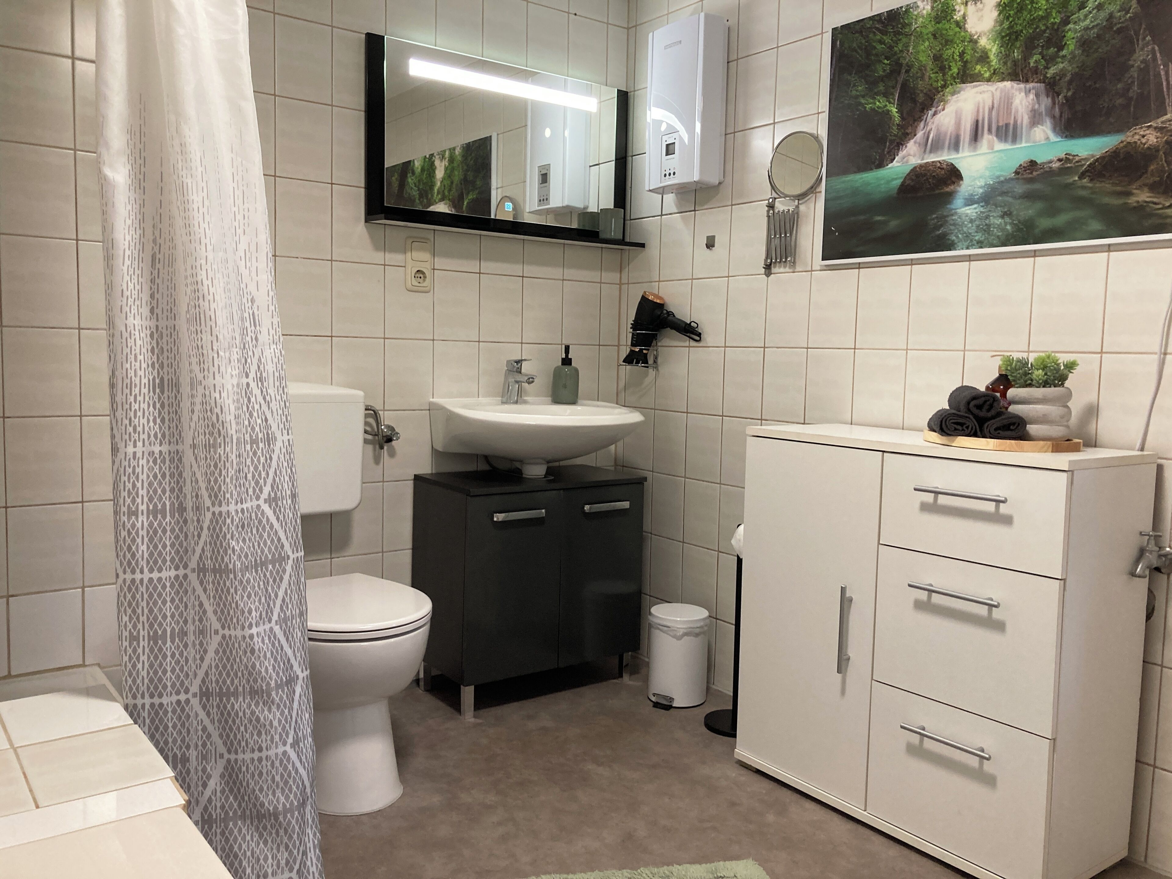 Une salle de bain comprenant des toilettes, un lavabo, un meuble et un miroir.