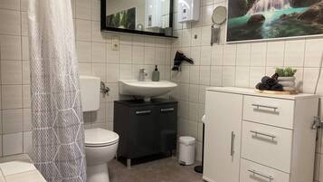 Une salle de bain comprenant des toilettes, un lavabo, un meuble et un miroir.