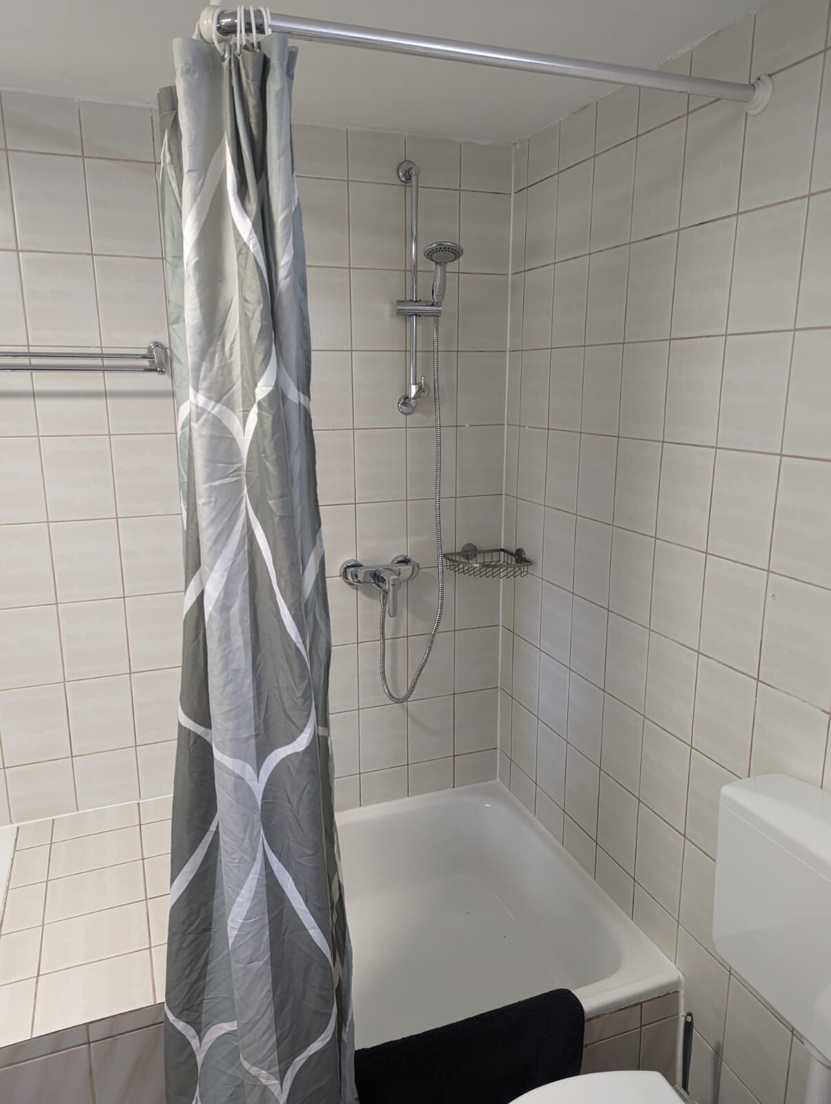 A bathroom with a shower, toilet, and a towel rack.
