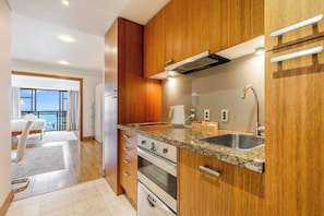Eine moderne Küche mit Holzschränken, Granit-Arbeitsplatten, einer Edelstahl-Spüle und einem eingebauten Backofen.