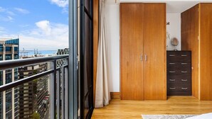 Une chambre dotée d’une grande fenêtre, d’une armoire en bois et offrant une vue sur le paysage urbain.