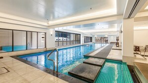 Une piscine intérieure à l’eau d’un bleu limpide, avec des marches carrelées et un design moderne.