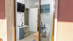 A modern hotel room with a glass door, a small kitchenette, a bathroom, and a bed. - Gallo's City Rooms (Termoli)