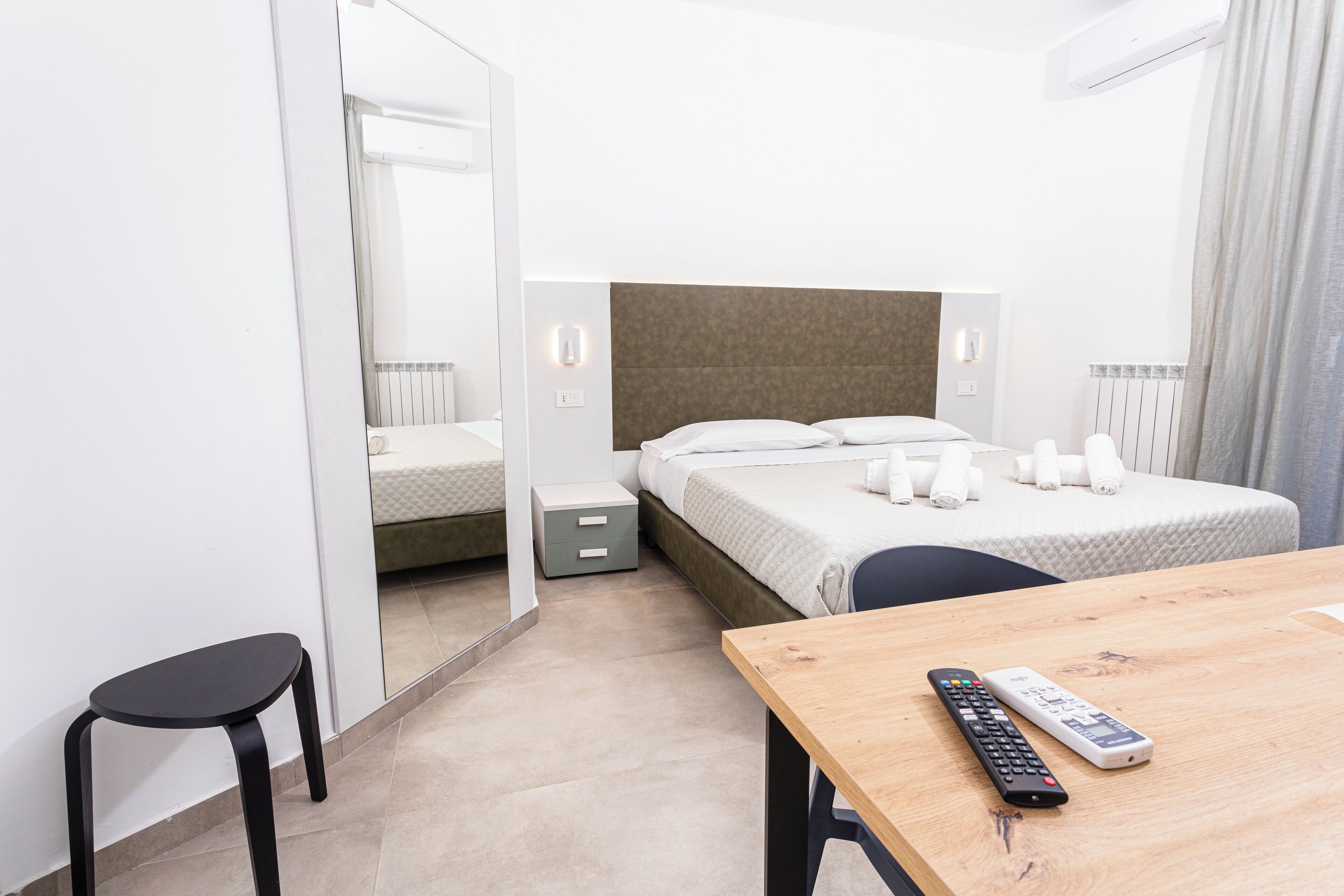 Una habitación de hotel con cama, mesita de noche y espejo.