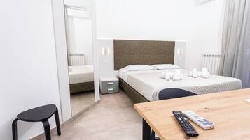 Una habitación de hotel con cama, mesita de noche y espejo.