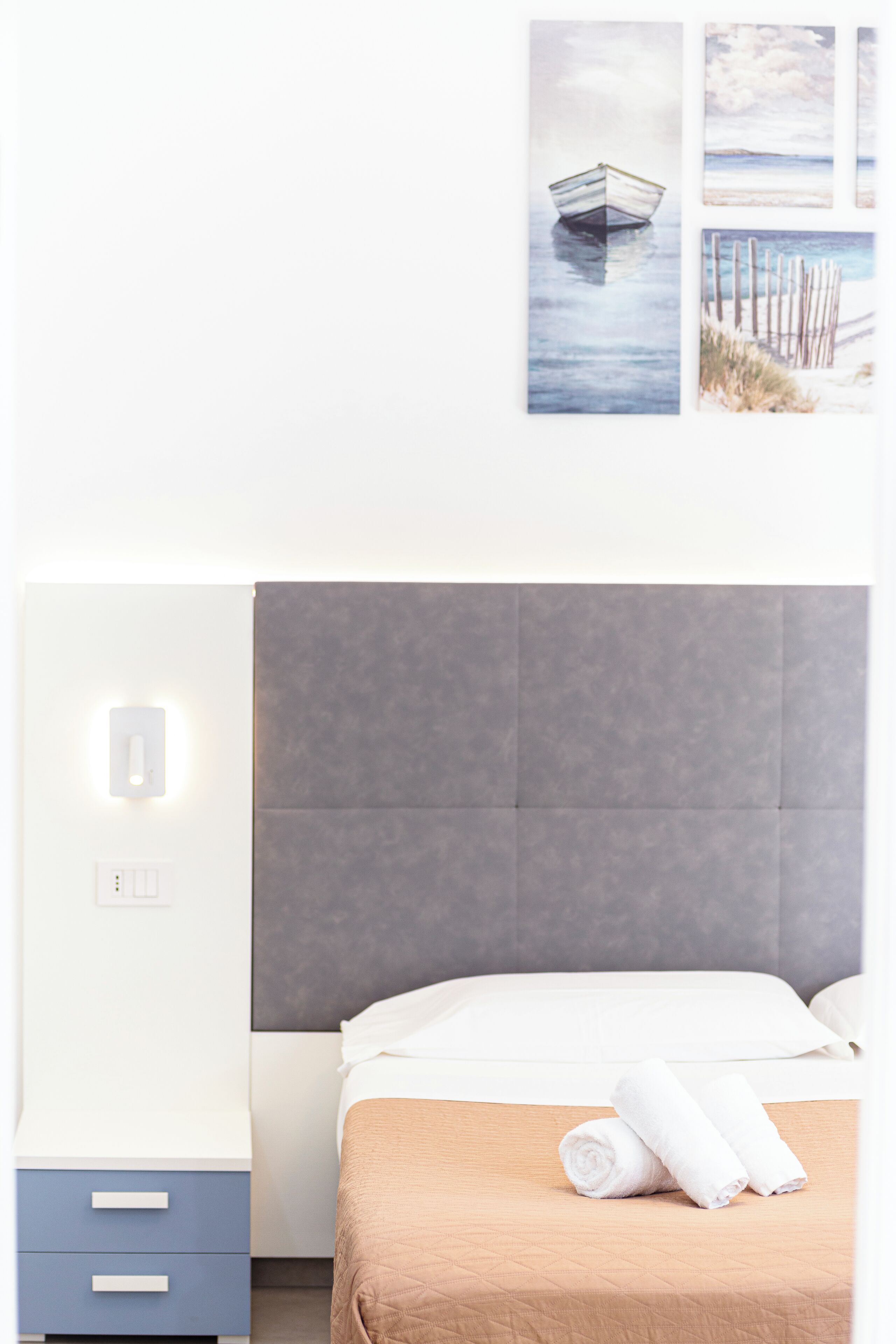 Une chambre d’hôtel avec un lit, une table de chevet et une lampe fixée au mur.