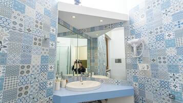 Un baño con pared de azulejos blancos y azules, un lavabo blanco y un espejo.