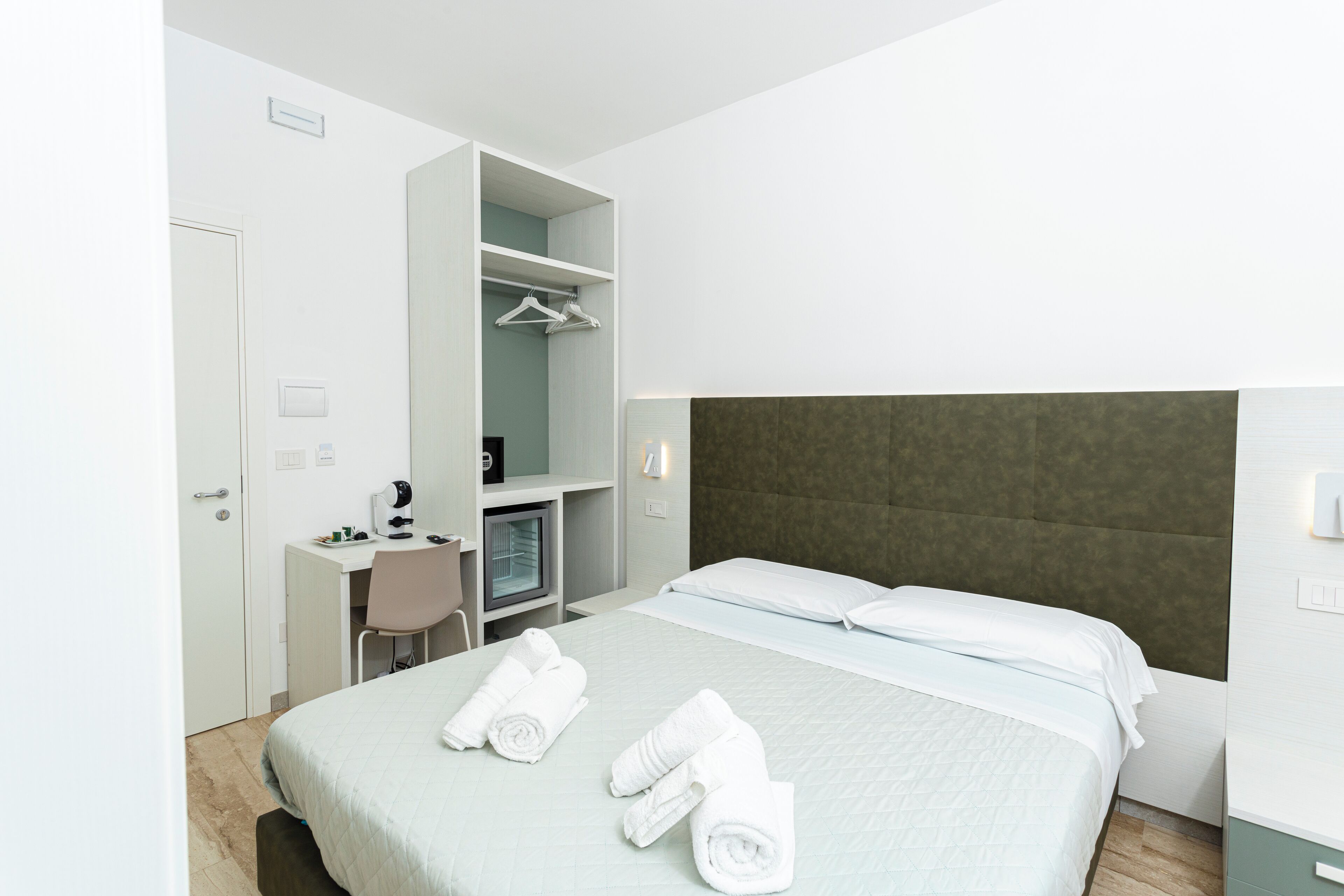 Una habitación de hotel moderna con cama, escritorio, silla y armario.