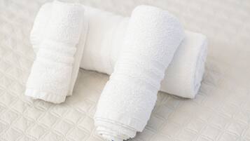 Une serviette blanche enroulée sur un couvre-lit matelassé.