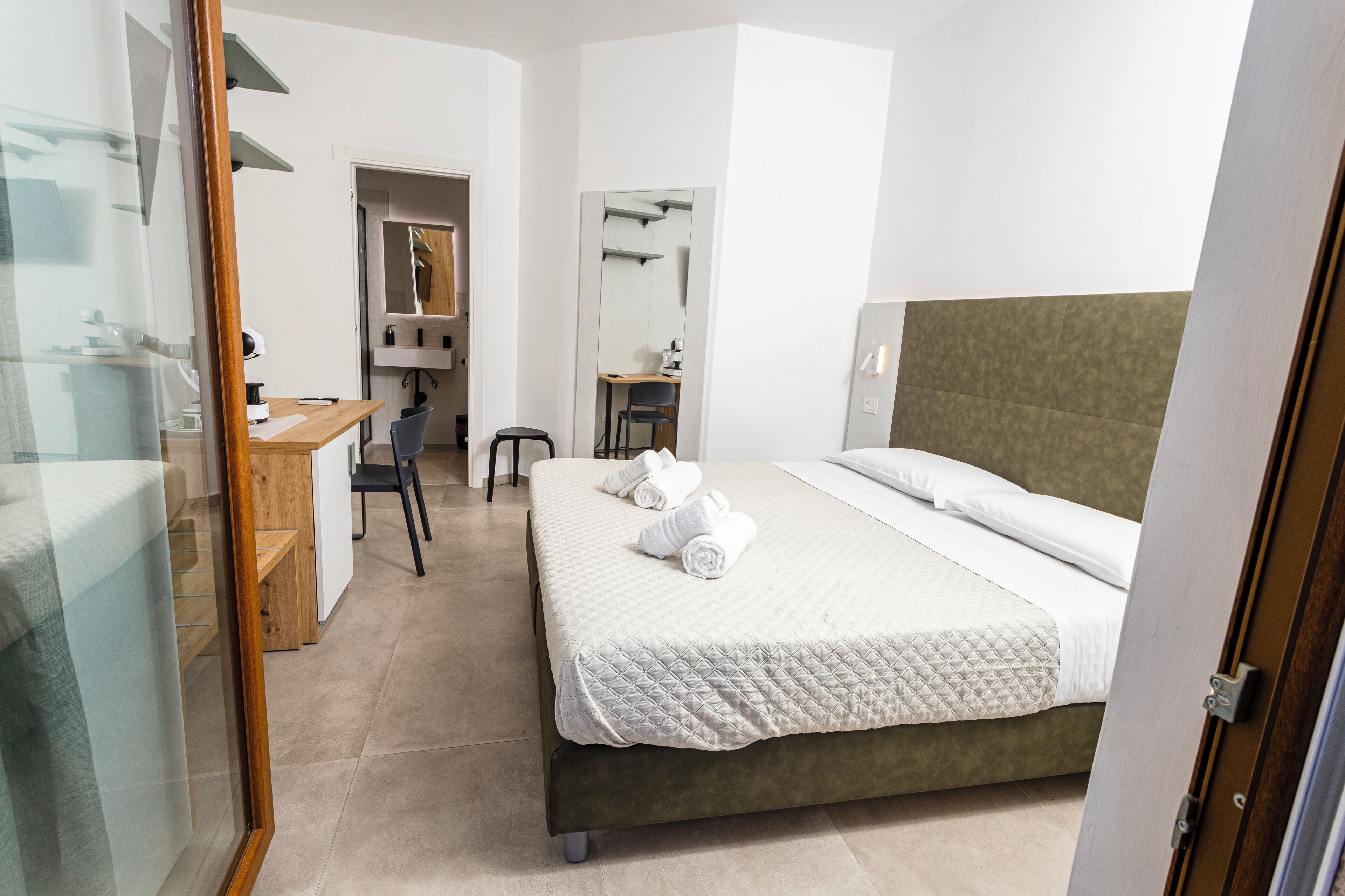 Une chambre d’hôtel avec un lit, un bureau, une chaise et un miroir.