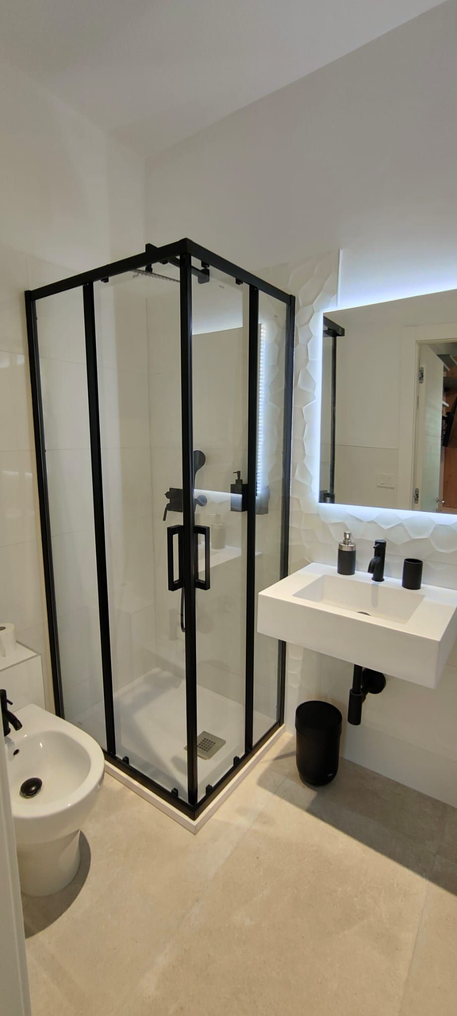 Un baño moderno con ducha envuelta en vidrio, un lavabo blanco y un espejo grande.